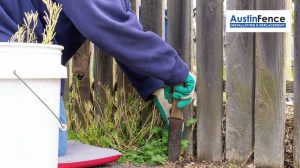 the contractor is removing the grass that is growing on the fence