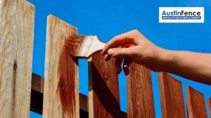 A person is staining a fence